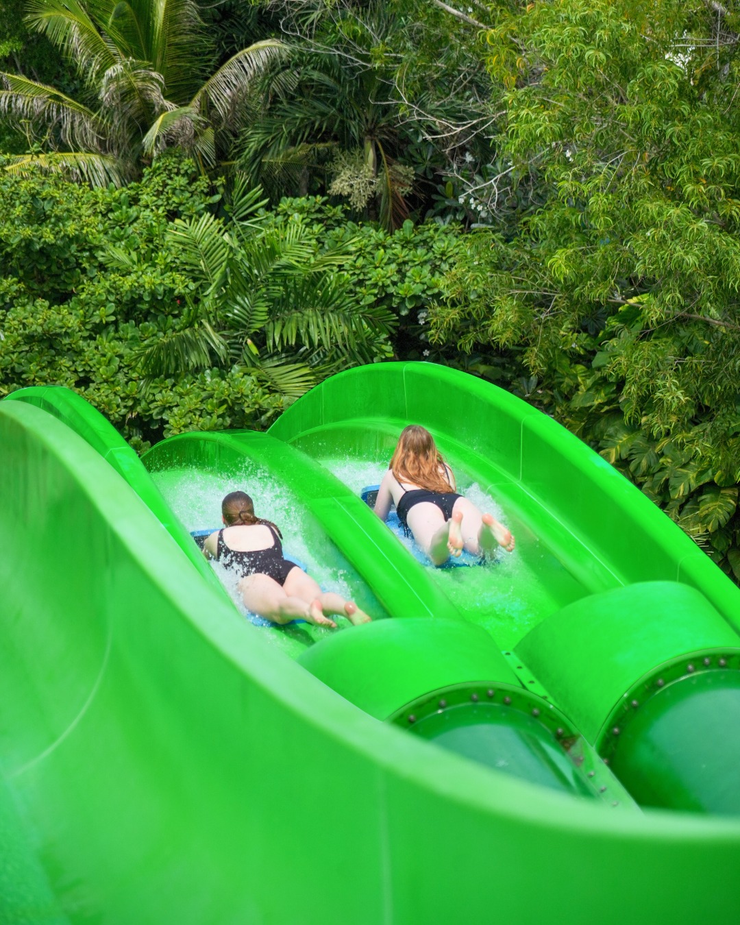 Two riders racing head-first down Twin Racers at Waterbom Bali